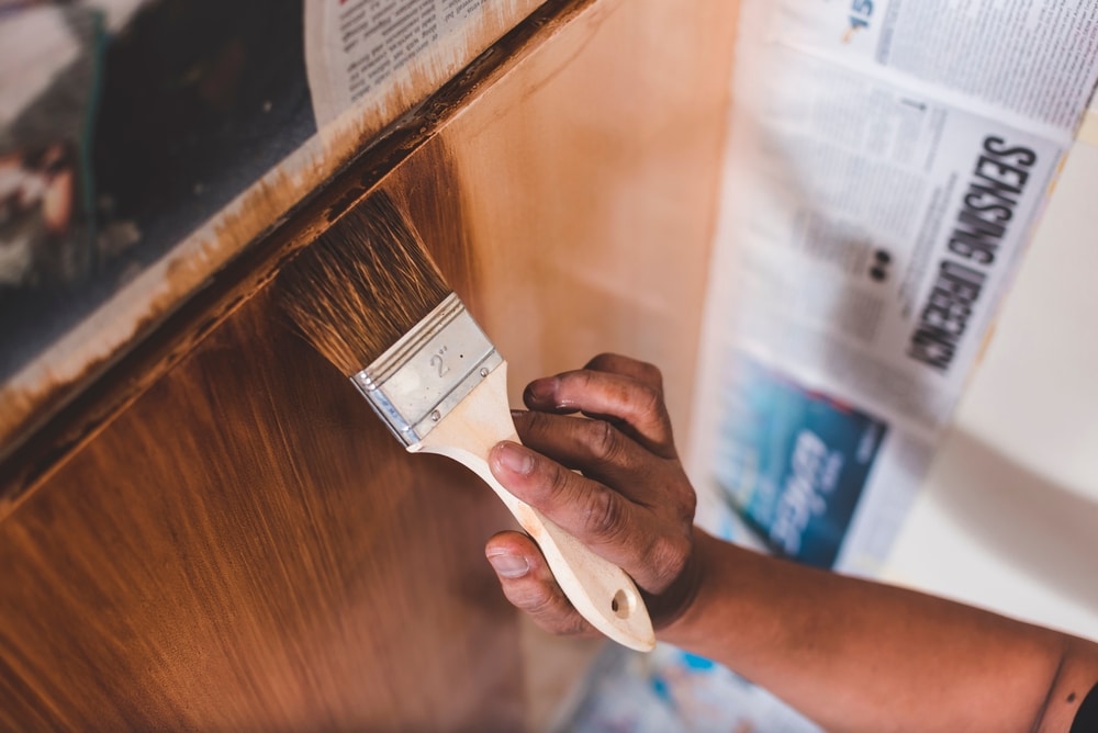 A view of a hand holding a brush to paint kitchen cabinet