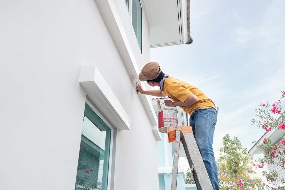 A view of a person painting the house exterior