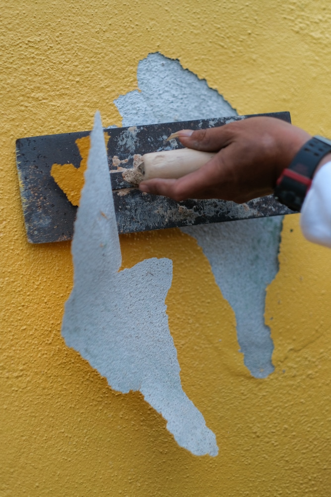 A view of a person scratching paint off a wall