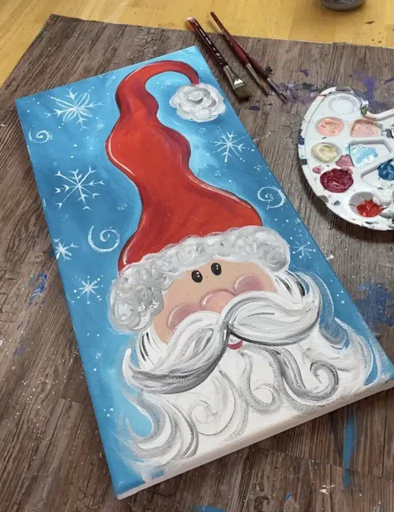 A Santa claus painting on a canvas placed at a wooden board