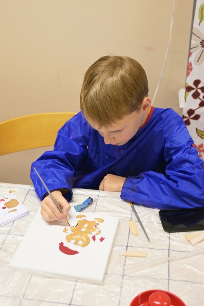 A view of a boy painting a gingerbread man