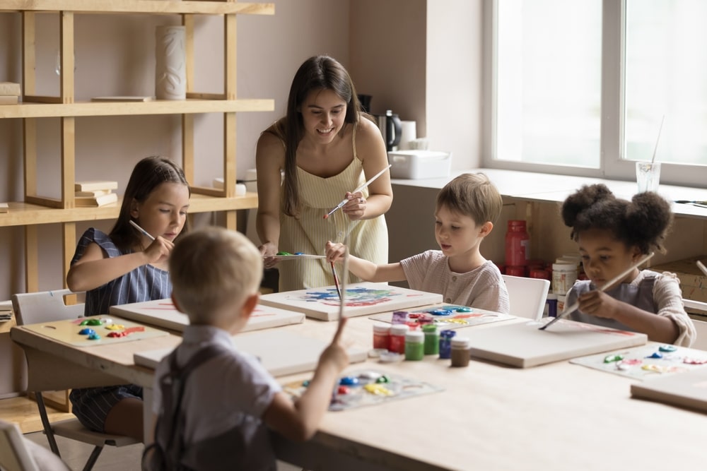 A view of a female teacher teaching kids how to paint