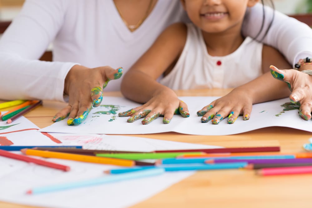 A view of a little girl hand painting with her teacher