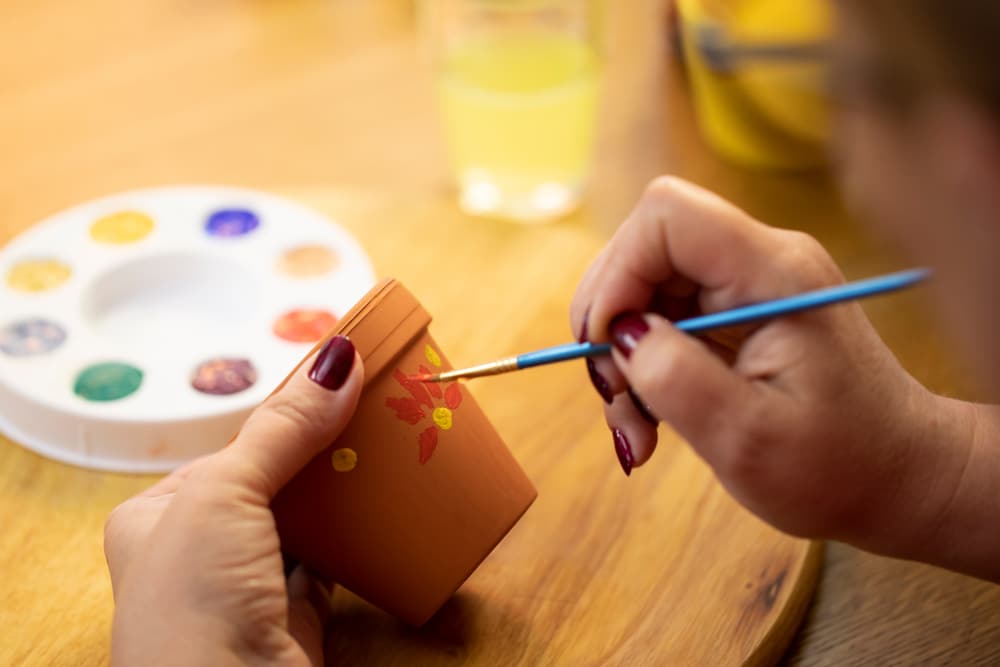 A view of a person painting a pot