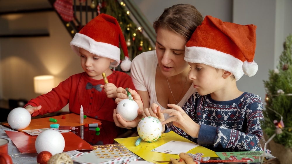 A view of children painting christmas balls with their mother