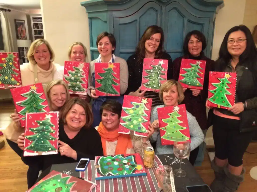 A view of people holding christmas tree painting and smiling