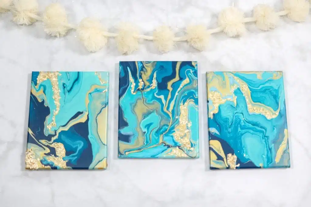 Three blue Pouring Wall Art paintings hung on a wall