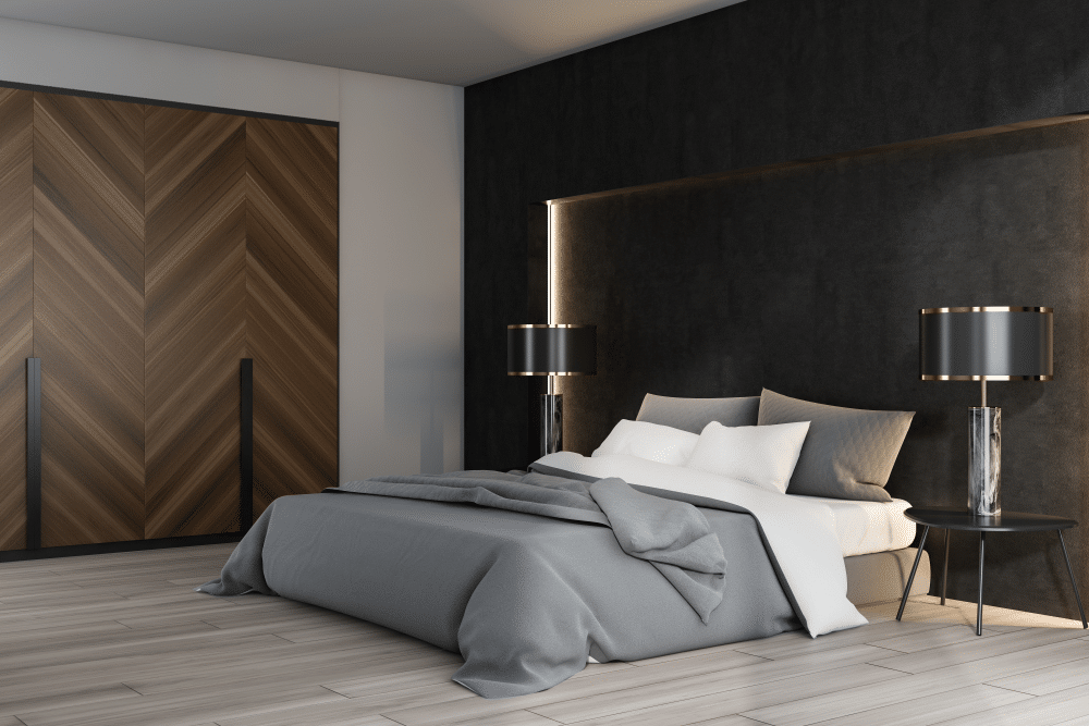 Black and white luxury bedroom interior with double bed standing on wooden floor and two original lamps on bedside tables