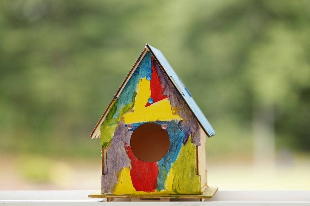 Colorfully Painted Birdhouse With Abstract Designs On A Blurred Natural