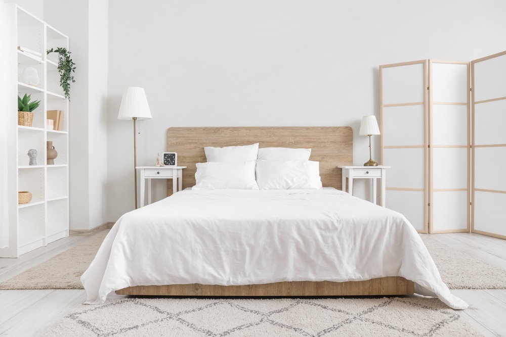 Interior Of Bedroom With Bed Shelving Unit And Folding Screen