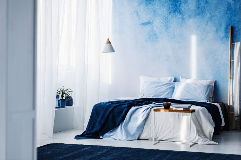 Table In Front Of Bed With Navy Blue Blanket In