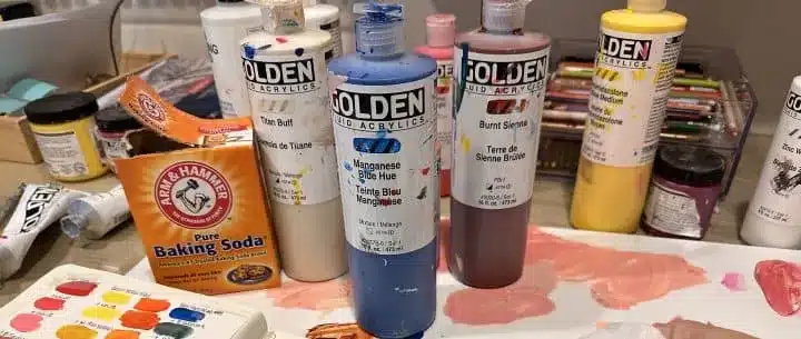 a box of baking soda with bottles of different acrylic paints