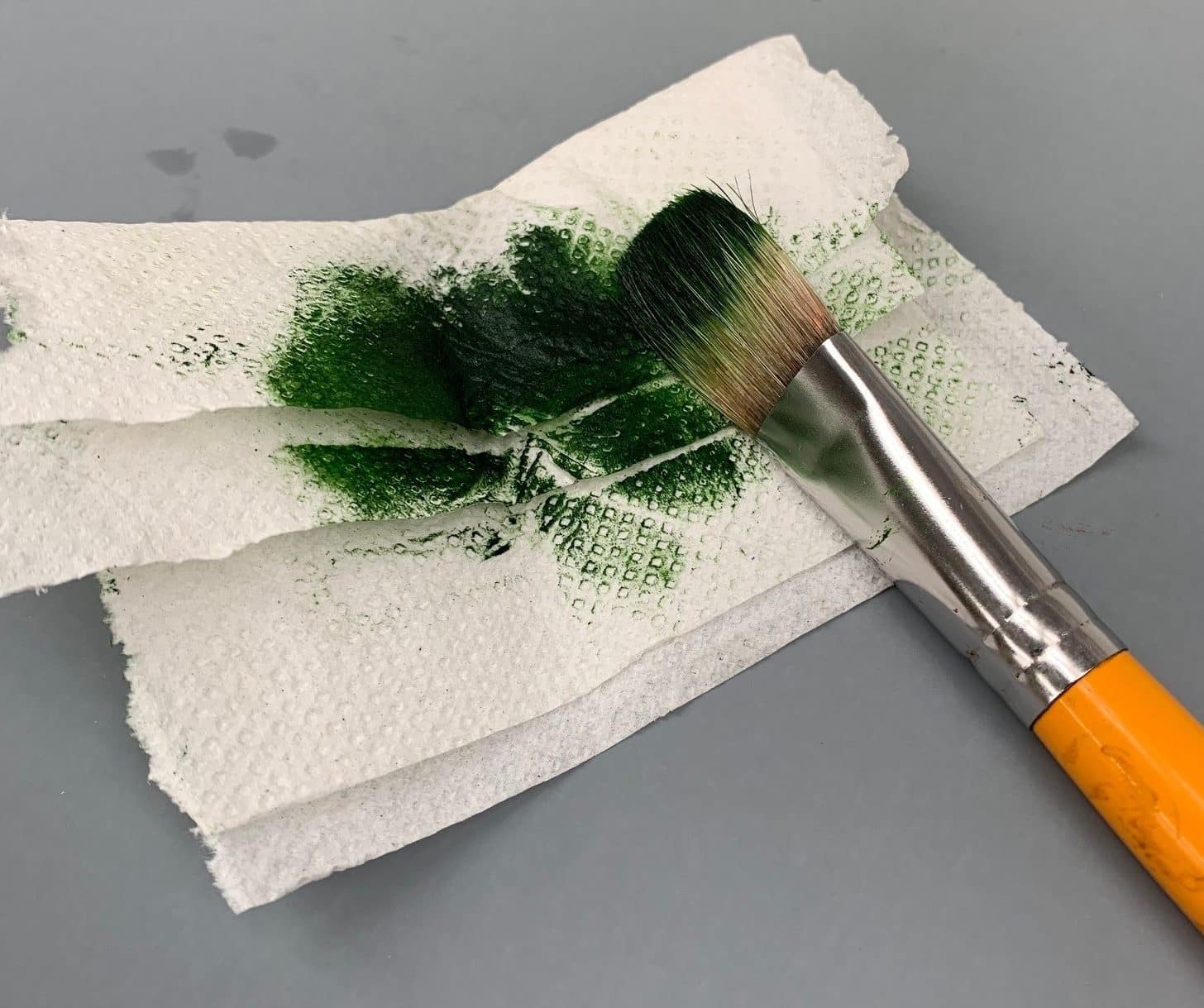 cleaning of a green paint brush with a tissue paper