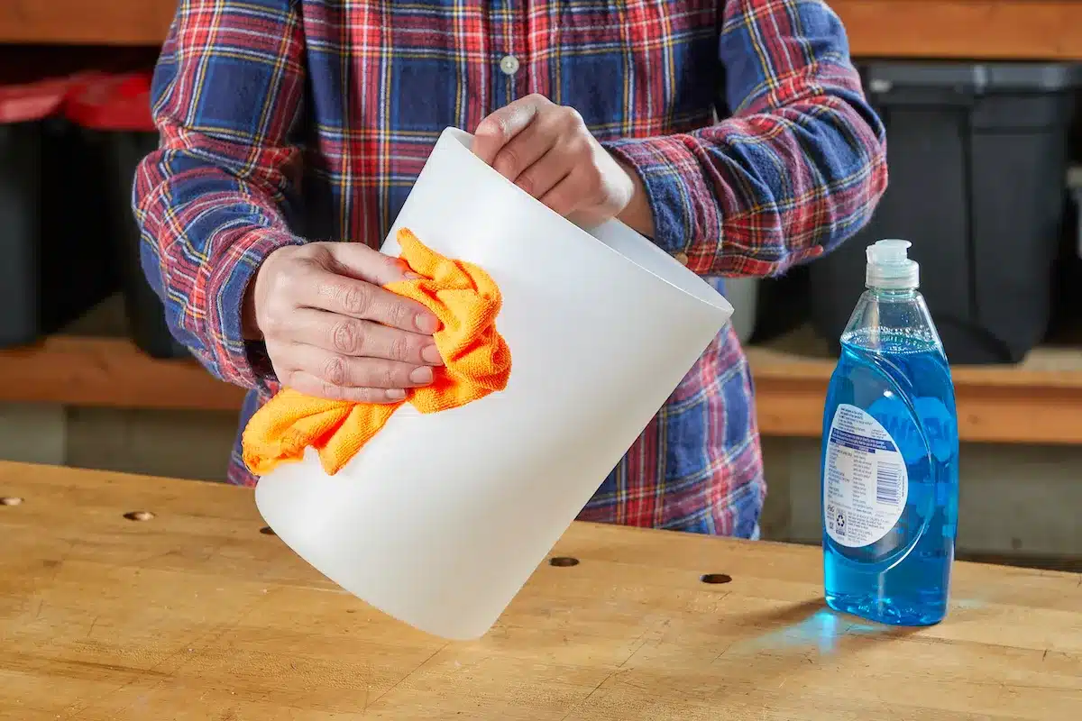 Person cleaning a plastic container with a cloth and dish soap Person cleaning a plastic container with a cloth and dish soap