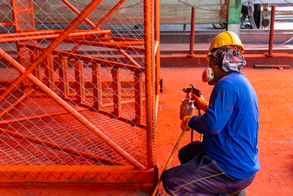 The painter is working to painting the steel structure with spray gun