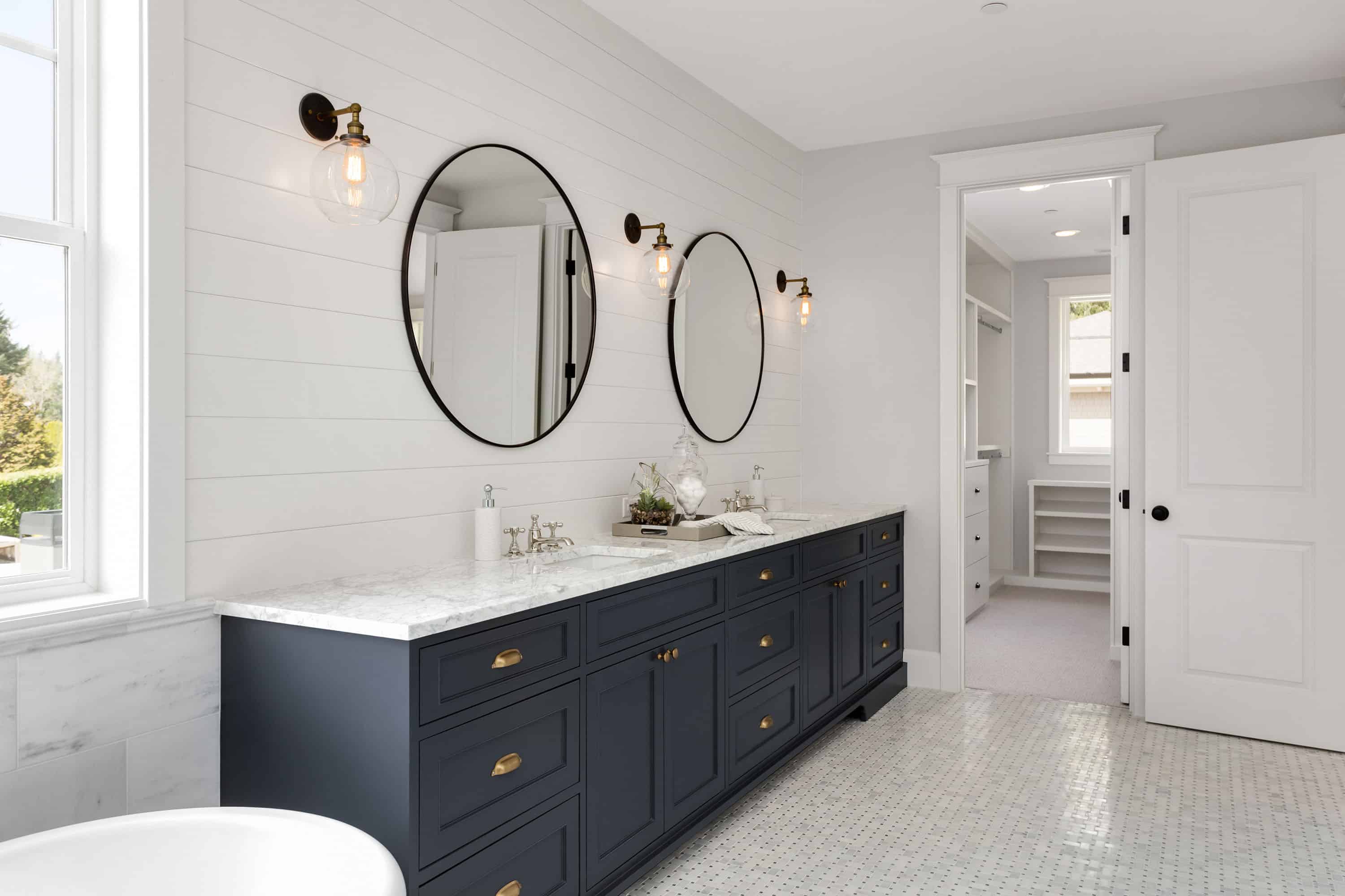 Bathroom in New Luxury Home with Two Sinks and Dark Blue Cabinets Shows Walk In Closet