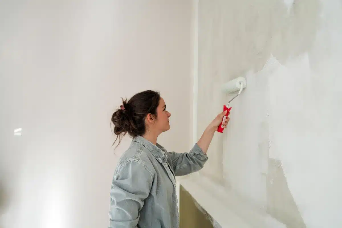 a girl fixing bubbling paint on wall