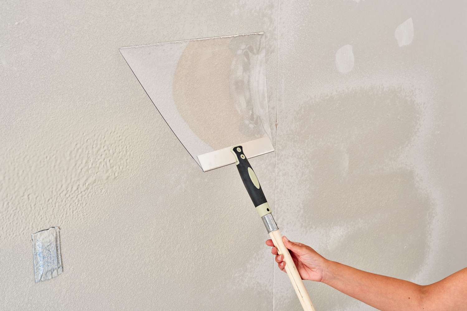 zoomed view of a hand applying knockdown texture paint on a wall zoomed view of a hand applying knockdown texture paint on a wall