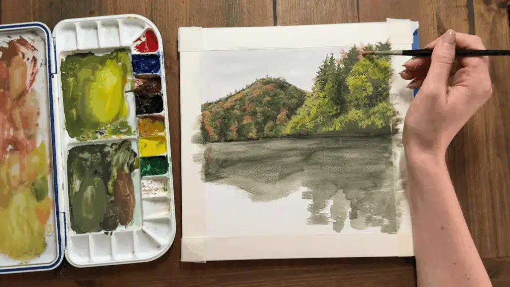 close up of a female hand painting a tree with gouache paint