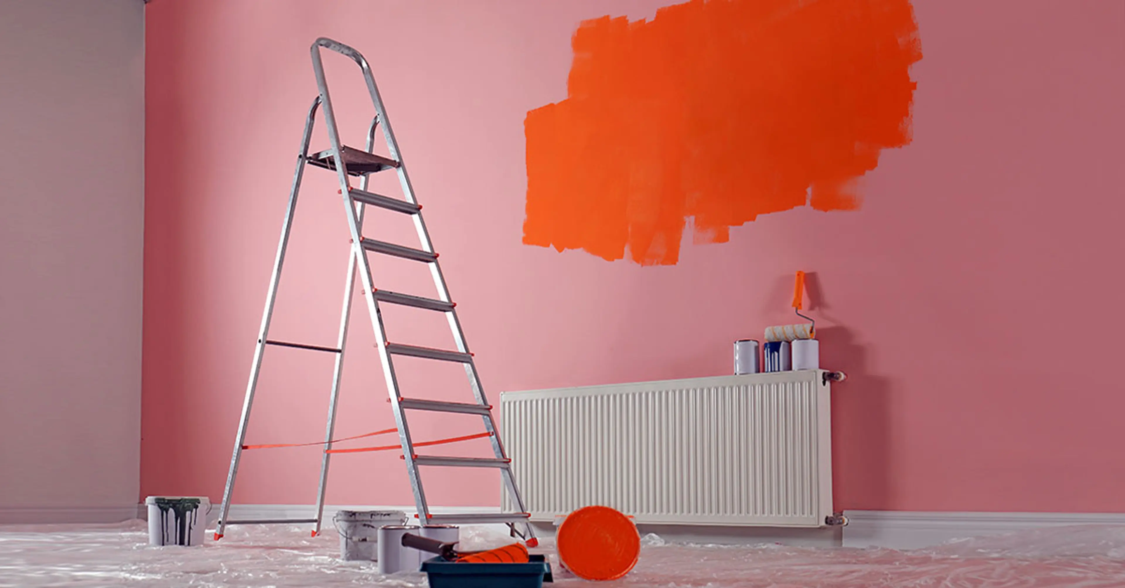 a pink wall with a patch of orange paint a ladder and paint bucket