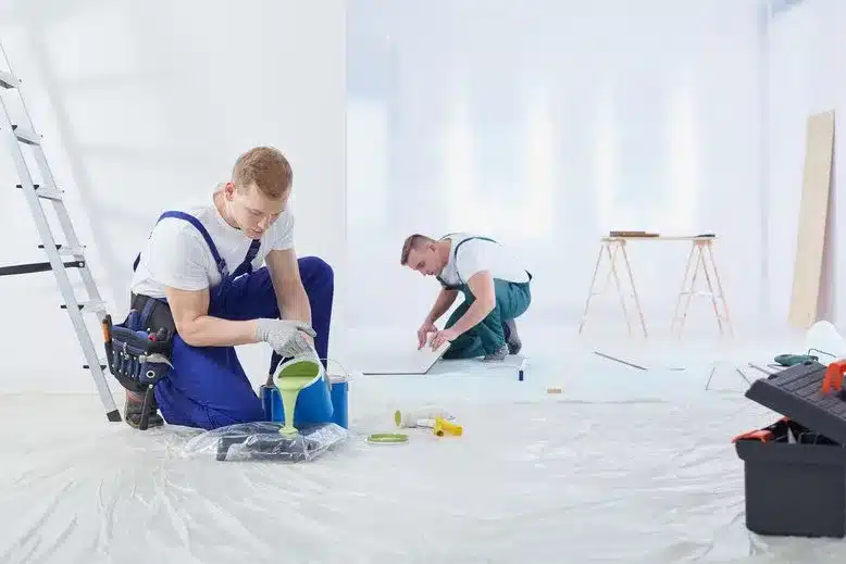 Two workers preparing for a painting job in a room