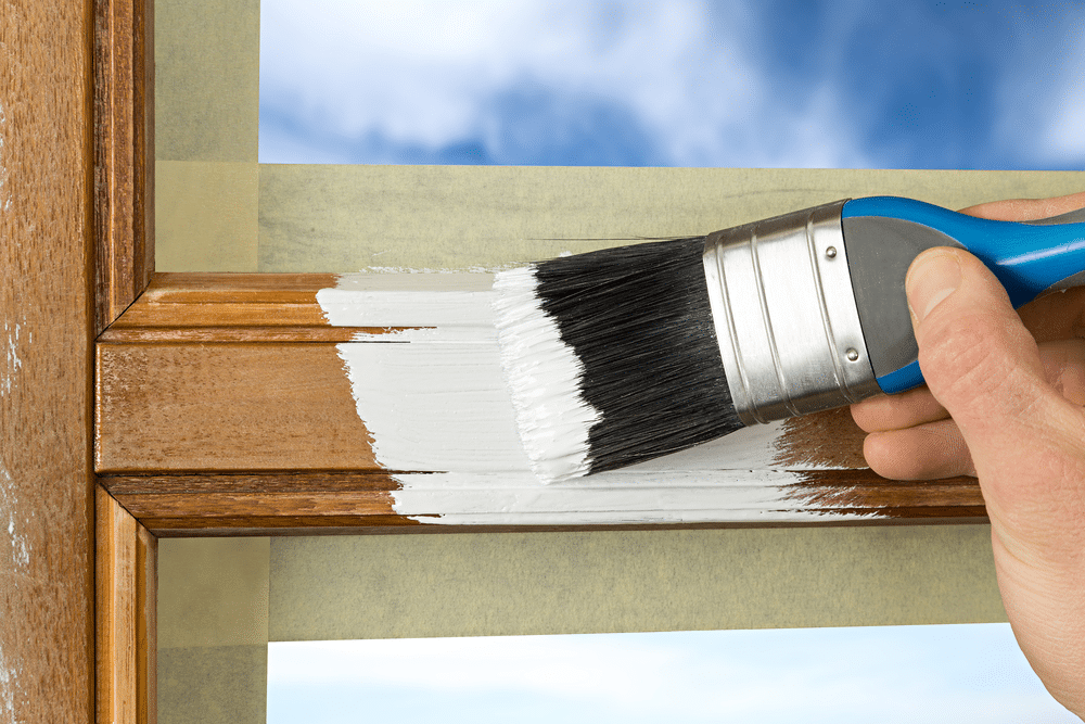 A close view of a person painting a window frame with a brush A close view of a person painting a window frame with a brush
