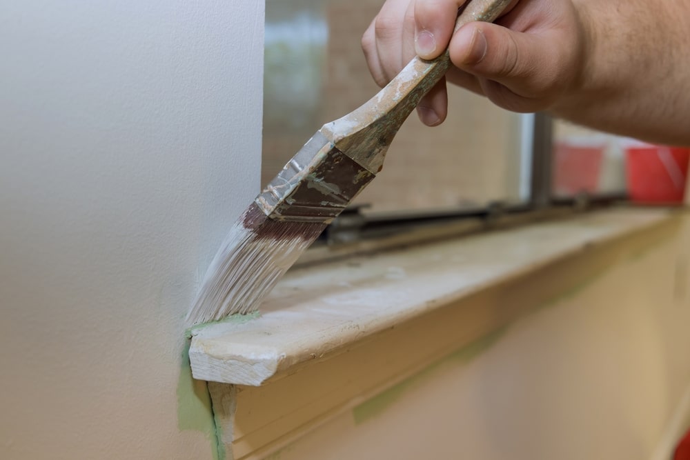 A view of a hand brushing the corners of a window sill A view of a hand brushing the corners of a window sill