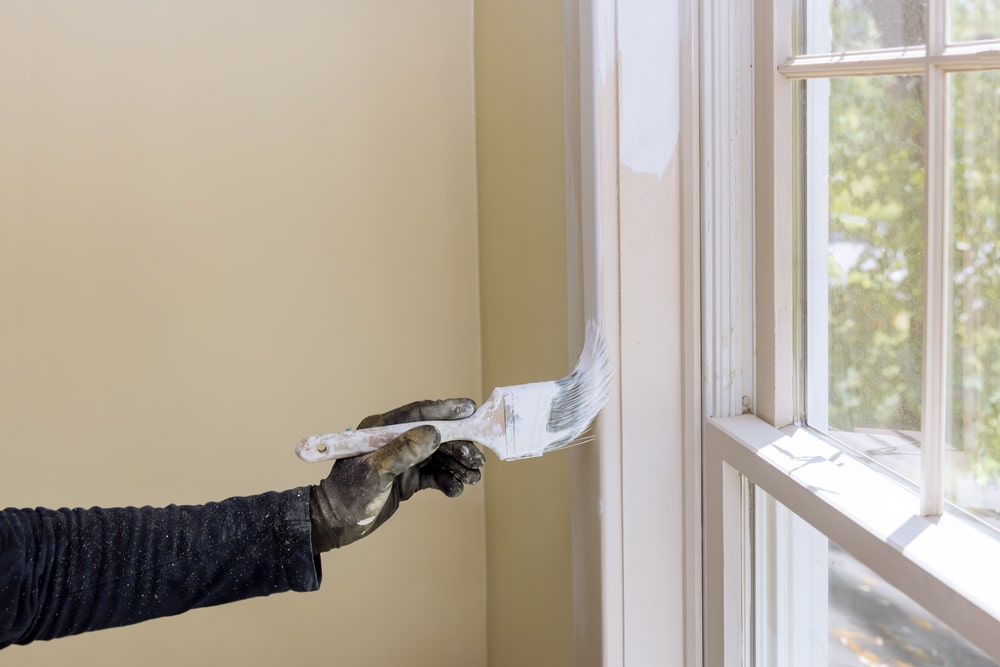 A view of a hand of repairman painting the trim A view of a hand of repairman painting the trim