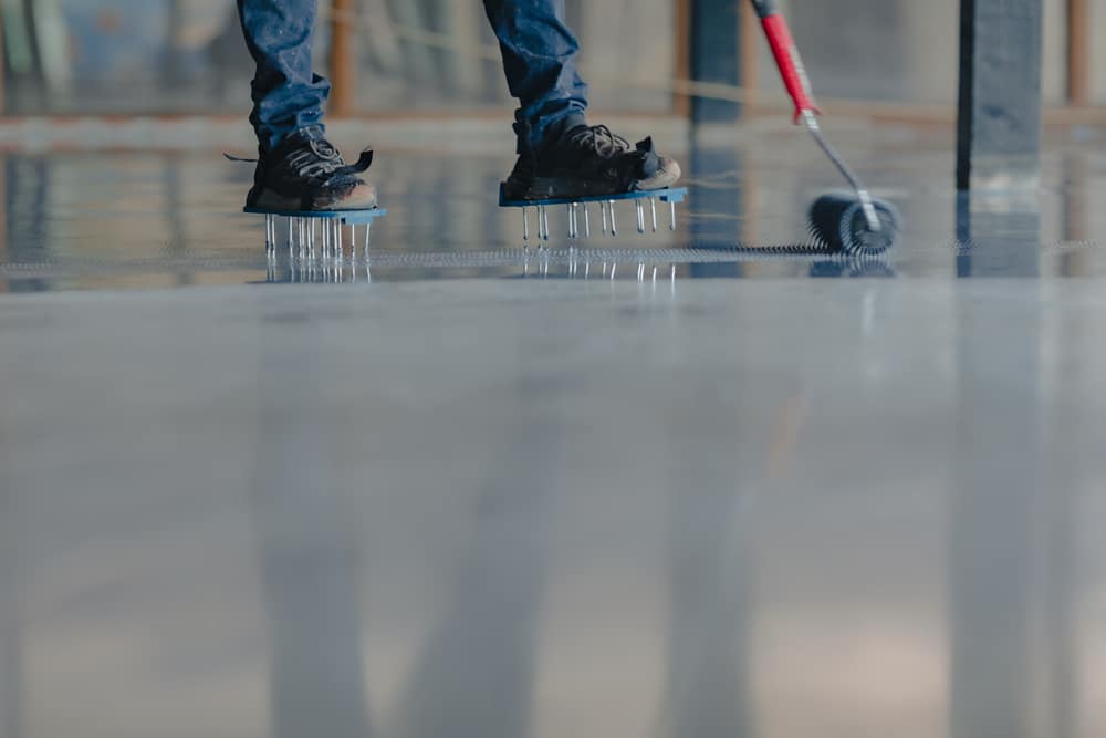 A view of a person painting garage floor with a roller A view of a person painting garage floor with a roller