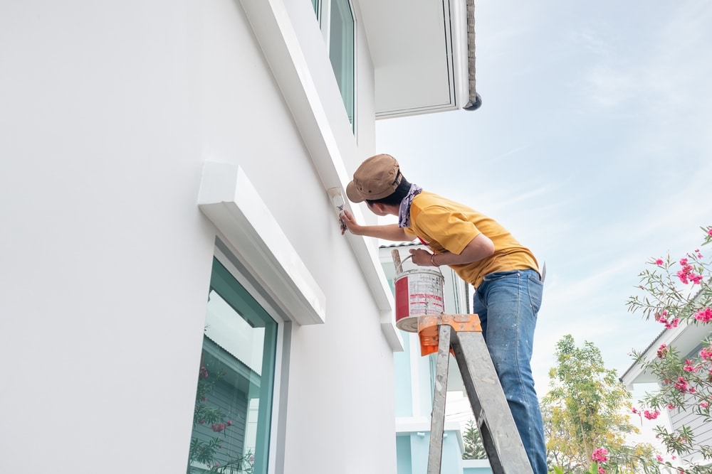 A view of a person painting the house exterior A view of a person painting the house exterior