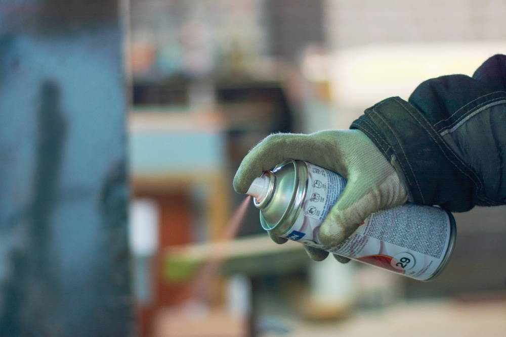 A view of a person spraying paint from a can A view of a person spraying paint from a can