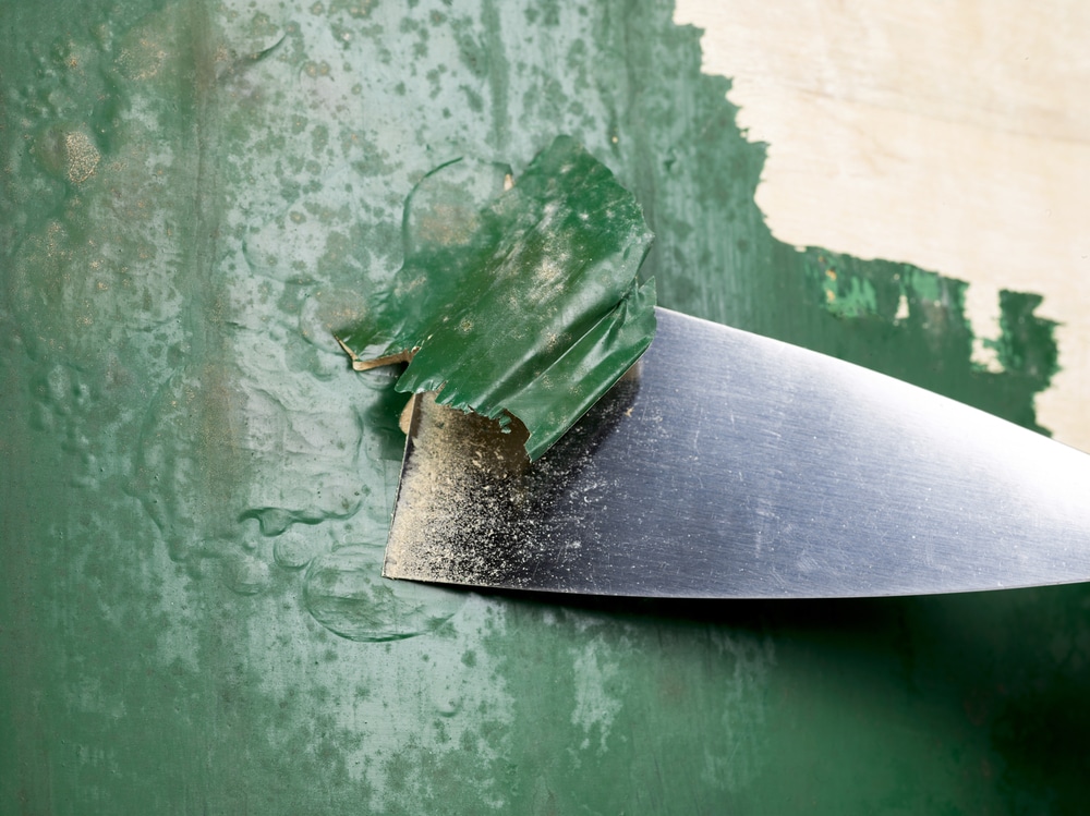 A view of green paint being stripped off a wall A view of green paint being stripped off a wall