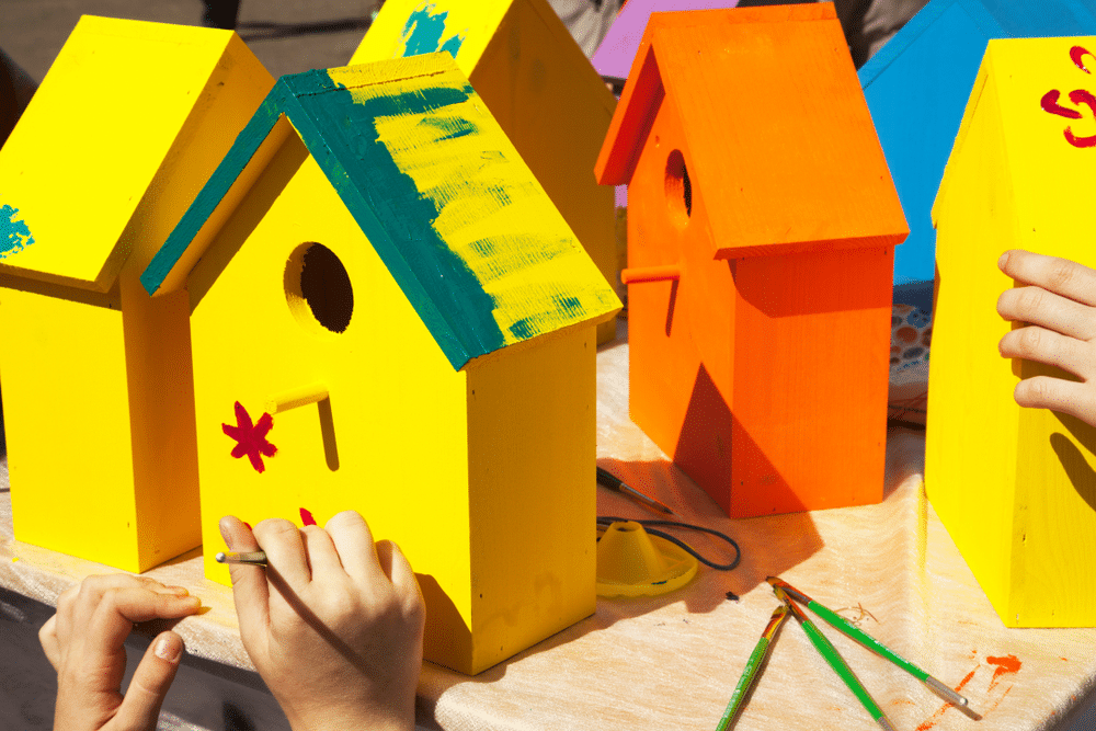 Children painting birdhouses bright colors of orange and yellow Children painting birdhouses bright colors of orange and yellow