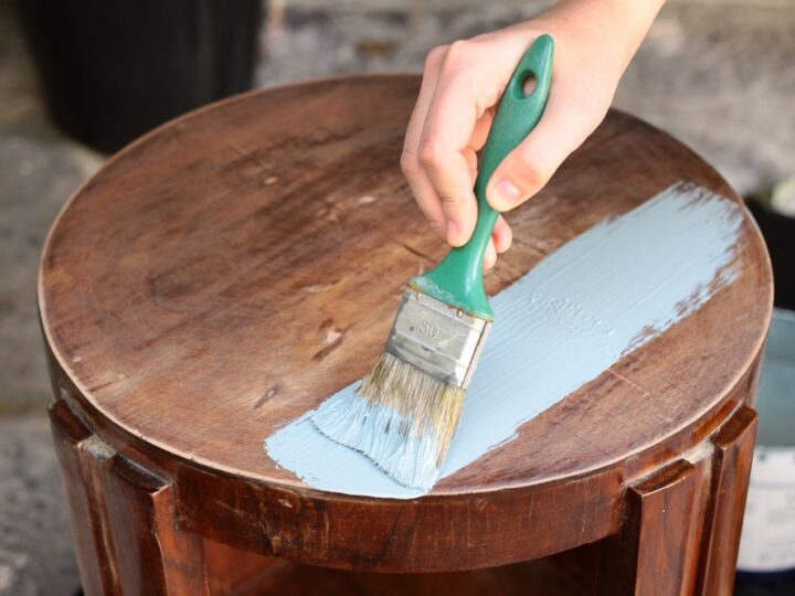 Close up view of human hand painting furniture