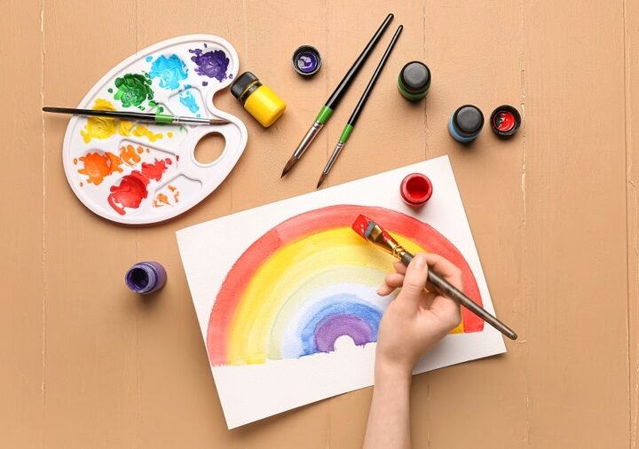 Female Hand Painting Rainbow On Paper Top View