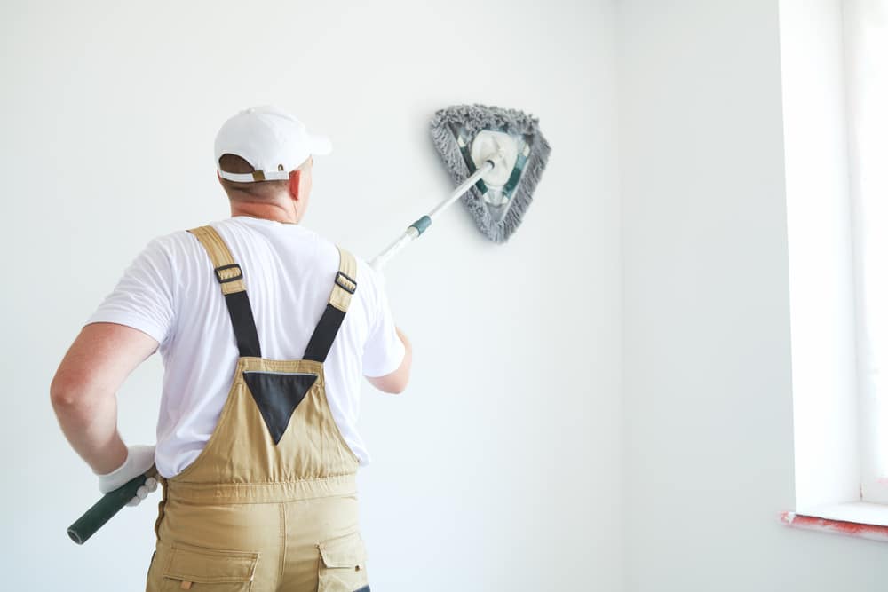 Painter works with triangle drywall cleaning tool Painter cleaning the wall with triangle drywall cleaning tool