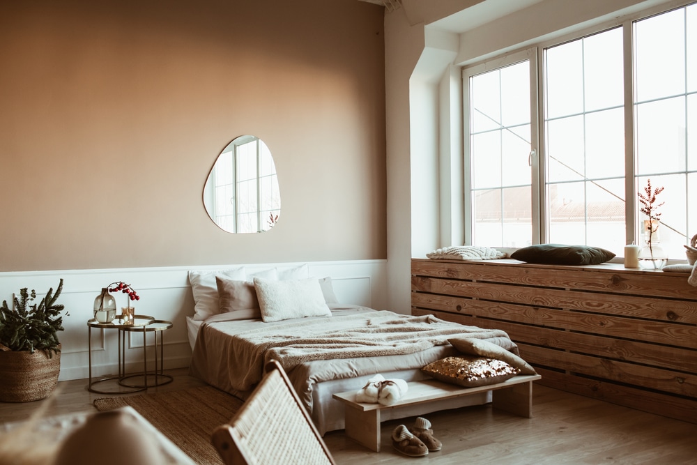 Stylish beige color bedroom with bed linen pillows mirror bedside table with red berries bouquet furniture Stylish beige color bedroom with bed linen pillows mirror bedside table with red berries bouquet furniture
