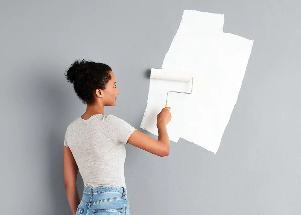 a girl applying primer paint on a wall a girl applying primer paint on a wall while not doing common painting mistakes