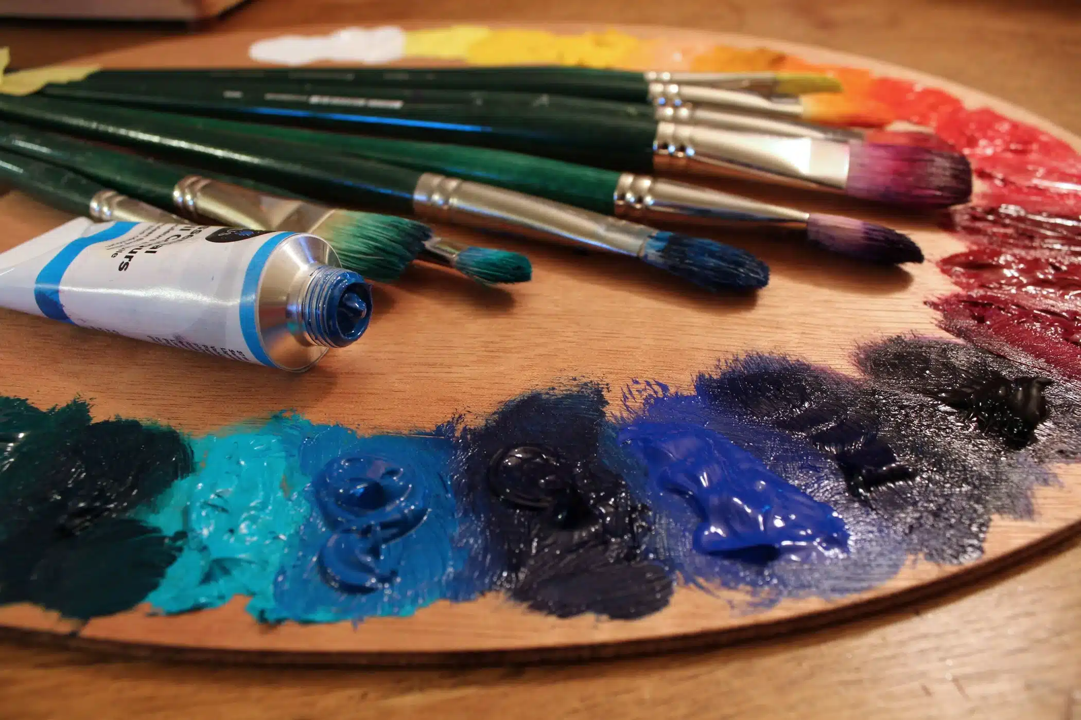 different oil paint colors on a painting board brushes and an oil paint tube