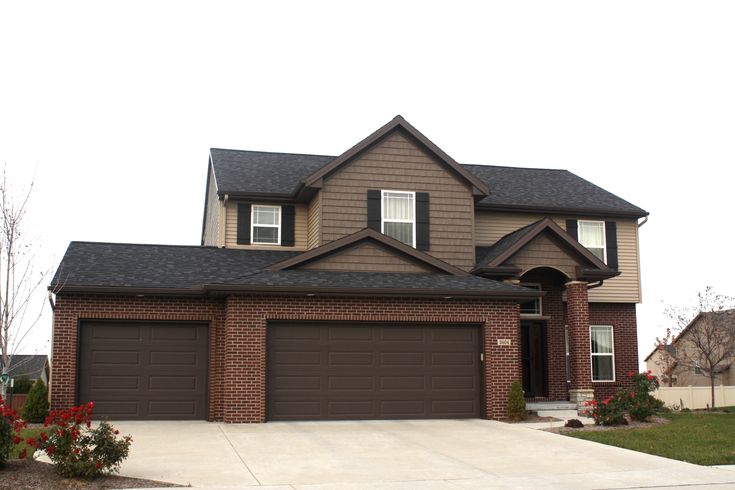 view of a beautiful brown house with black roof