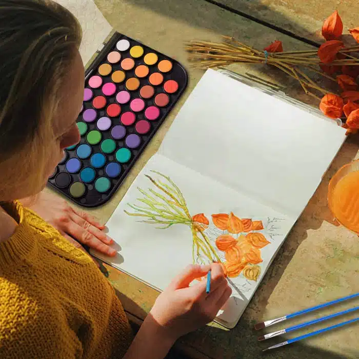 view of a lady painting on a paper with water colors